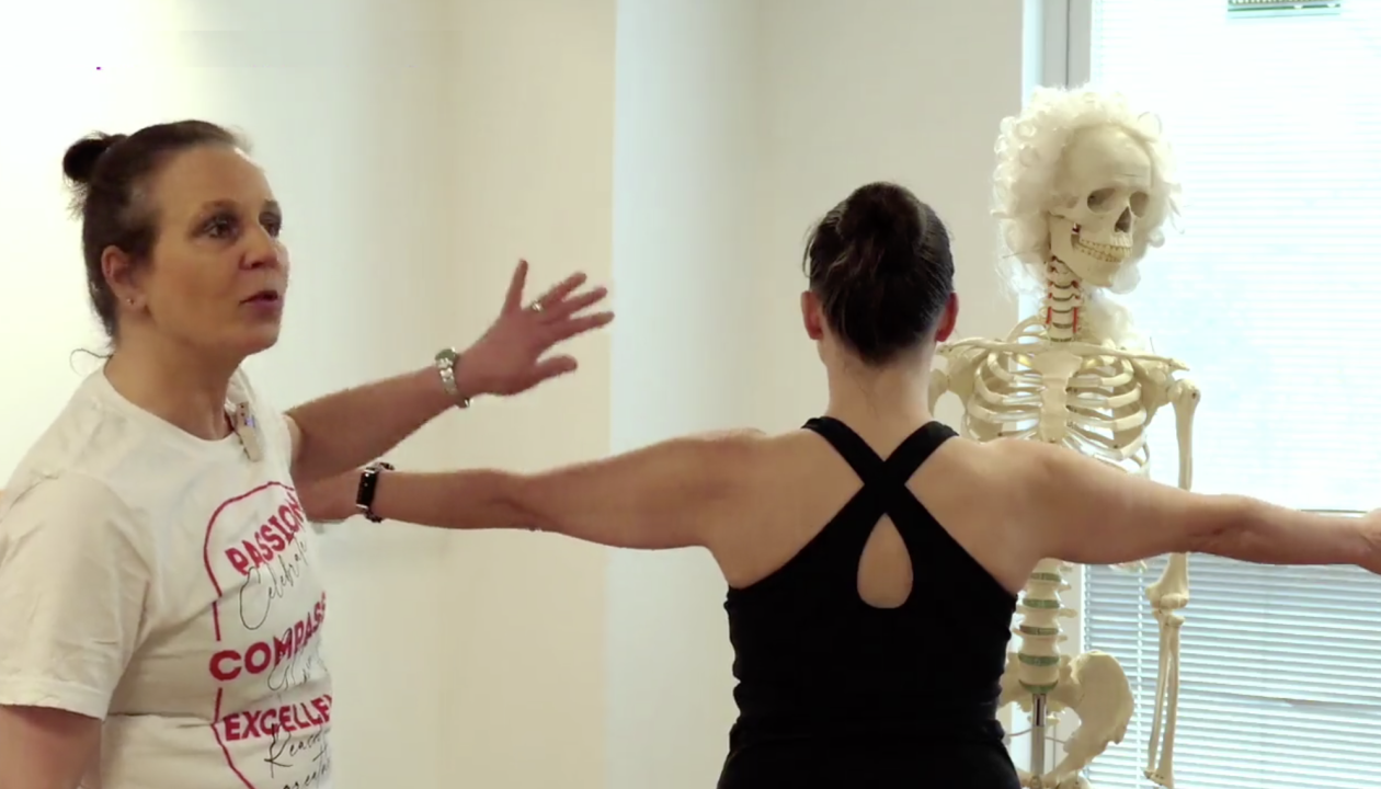 Natascha Eyber erklärt an der Schulter von Kerstin Bredehorn, dahinter steht ein Skelett