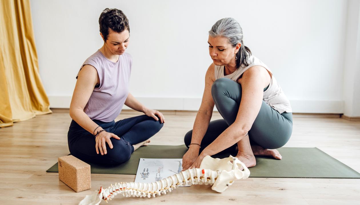 Antje Korte erklärt einer Pilates Schülerin die Wirbelsäule