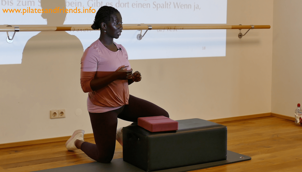 Juliana Afram kniet vor einer Box auf der zwei Yogablöcke liegen